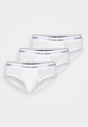 Witte katoenen slips in een verpakking van drie, met een zwarte merkband waarop "Calvin Klein" is gedrukt. Klassiek slipdesign.
