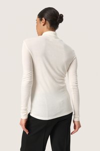 Long-sleeve, fitted turtleneck sweater in light cream, made from soft, smooth fabric. Features a slim silhouette with ribbed cuffs.