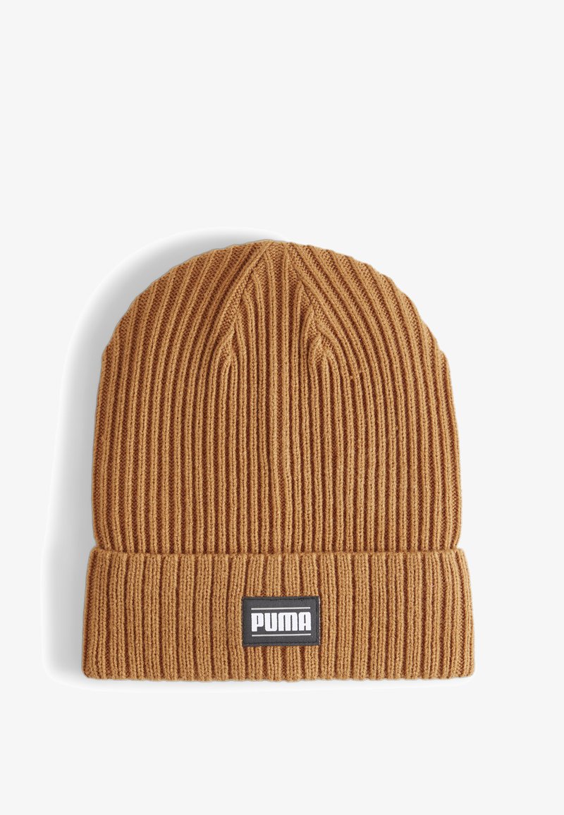 Brown knit beanie made from ribbed fabric, featuring a fold-over cuff and a black PUMA logo patch on the front. Textured and warm.