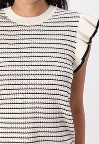 Strikket genser med rund hals, korte volang-ermer, beige med svarte horisontale striper og små åpne strikkedetaljer.