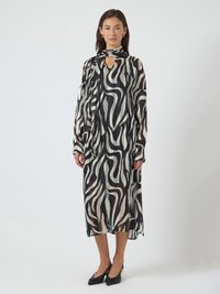 Vestido com estampa de zebra a preto e branco, feito de tecido leve e transparente. Apresenta um decote com abertura em forma de gota e mangas compridas com detalhe de laço.
