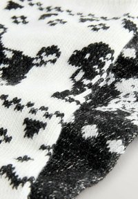 Gestrickter, gemusterter Schal in Schwarz und Weiß, der geometrische Formen mit unterschiedlichen Texturen, weichen Fasern und einem lässigen, gemütlichen Design aufweist.