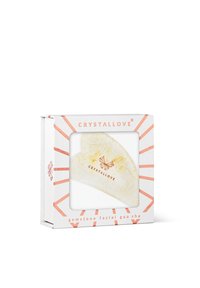 Strumento gua sha in forma di cuore in pietra preziosa bianca con logo dorato. Imballato in una scatola bianca con accenti corallo e pattern a raggi di sole.