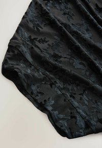 Black fabric with a floral velvet pattern, smooth texture, and subtle sheen; drapes elegantly with a flowing shape and soft finish.