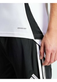 T-shirt de sport noir et blanc avec le logo "AEROREADY", présentant des panneaux latéraux contrastants, une texture de tissu lisse et une coupe ajustée.