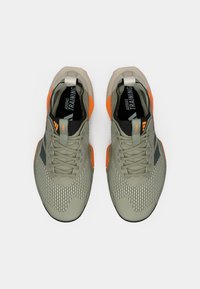 Αθλητικά παπούτσια ανοιχτό γκρι με επάνω μέρος από δίχτυ, πορτοκαλί λεπτομέρειες και υφή στη σόλα. Διαθέτουν κορδόνια και θηλιά για εύκολο φόρεμα.