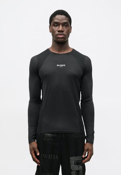 Schwarzes Langarmshirt aus glattem, elastischem Material mit Rundhalsausschnitt. "SILENCE"-Logo in Weiß in der Mitte der Brust.