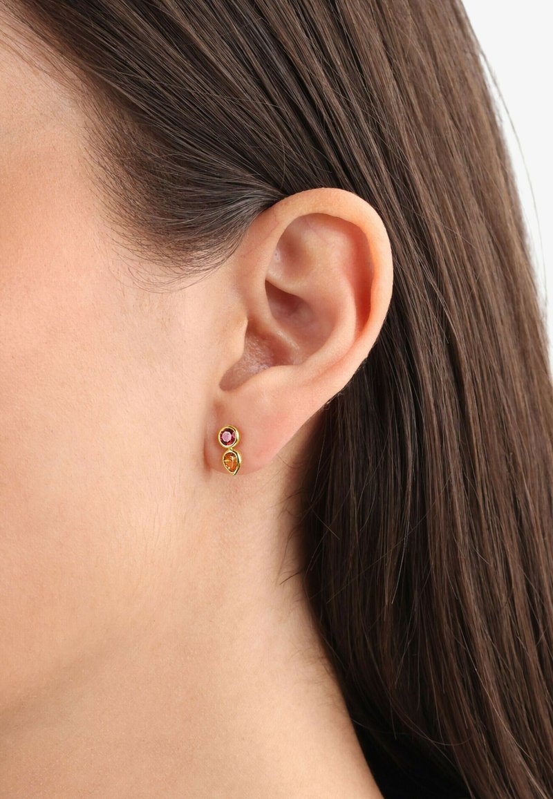 Pendientes de botón en tono dorado con un diseño en espiral, que presentan una gema rosa y naranja. Pequeños y delicados, ideales para el uso diario.