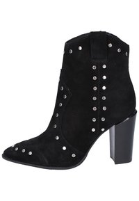 Bottine en suede noire avec des clous argentés, à bout pointu et un talon épais noir. Elle présente une languette à l'arrière pour un enfilage facile.