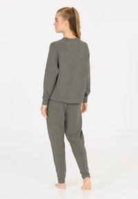 Grijze, lichte sweatshirt met raglanmouwen, gecombineerd met bijpassende taps toelopende joggers. Zachte textuur, minimalistisch ontwerp en een relaxte pasvorm.
