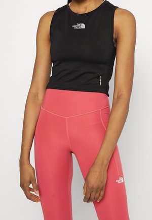Kobieta ubrana w czarny bezrękawnik sportowy top oraz różowe legginsy z wysokim stanem, z logo The North Face na obu elementach odzieży.