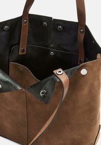 Borsa a tracolla in suede marrone con interno in pelle nera, manici in pelle marrone e chiusure a pressione sui lati e nella tasca interna.