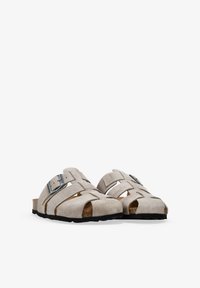 Sandalias de ante gris claro con diseños troquelados, correa ajustable con hebilla de metal y suelas de goma negra.