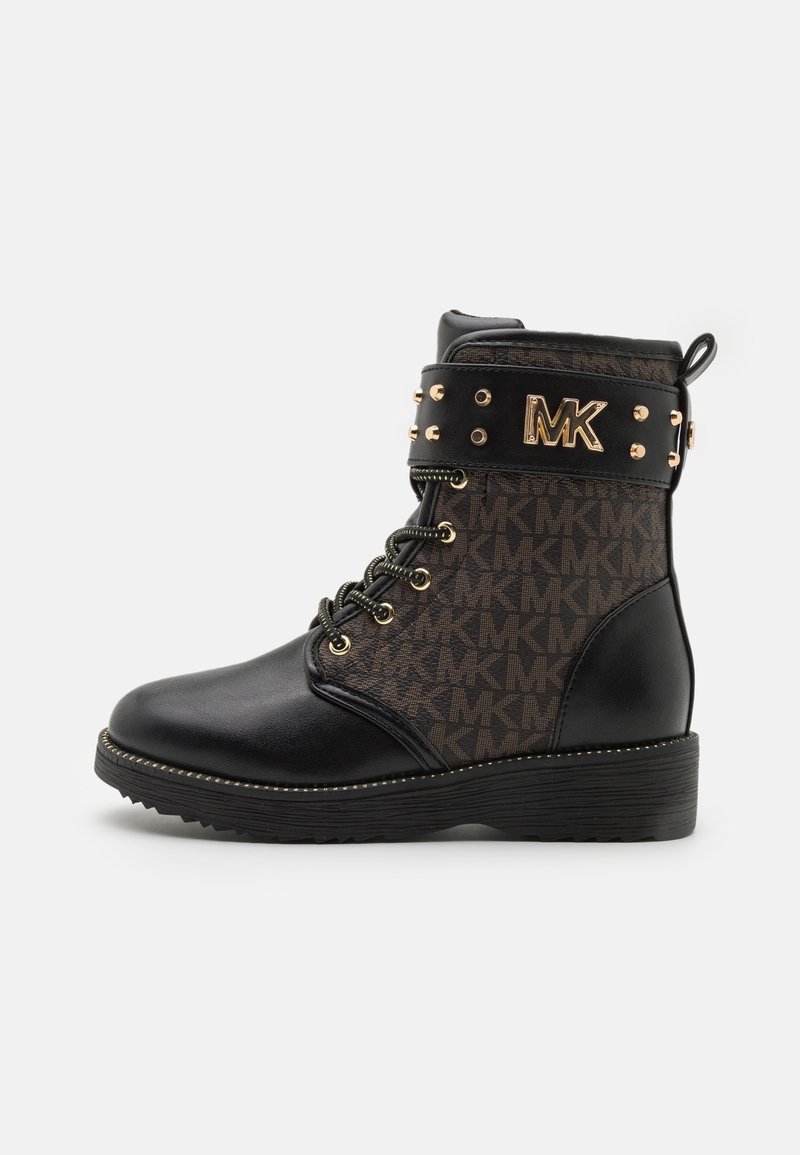 Bottine à lacets noire et marron avec clous dorés et logo MK sur le revers, semelle texturée et languette au dos.