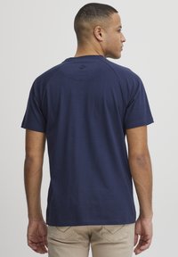 Mornarsko modra bombažna majica z okroglim izrezom in kratkimi raglan rokavi. Gladka tekstura brez vidnih vzorcev, logotip na hrbtu.