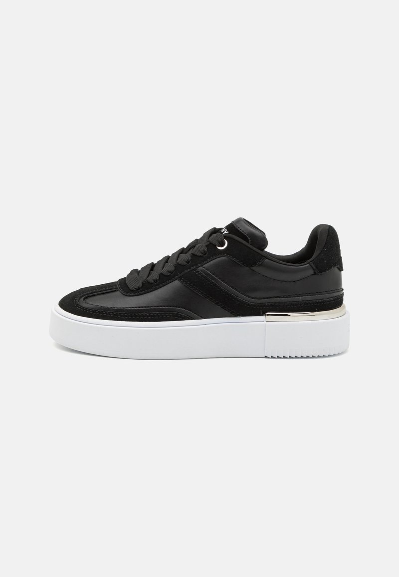 Black sneaker with a smooth leather upper, suede accents, flat laces, and a thick white platform sole with a textured tread.