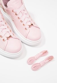 Baskets en cuir rose avec une texture lisse, semelle en caoutchouc blanche et œillets en or rose. Comprend deux lacets roses supplémentaires.