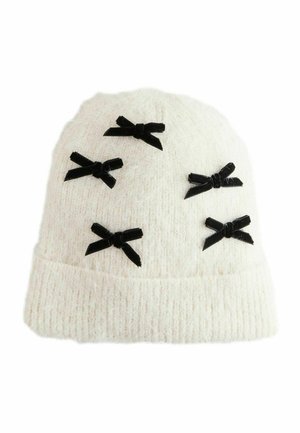Weiße Strickmütze, geschmückt mit sechs schwarzen Samt-Schleifen. Texturiertes Material mit einem umgeschlagenen Bund am unteren Ende verleiht dem Design Detail.