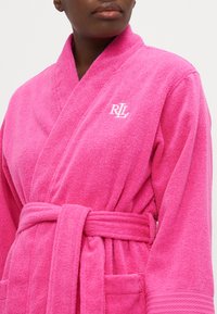 Ροζ πετσετέ ρόμπα με μαλακή υφή, σχεδίαση που αγκαλιάζει το σώμα, ζώνη και κεντητό λογότυπο "RL" στο στήθος.