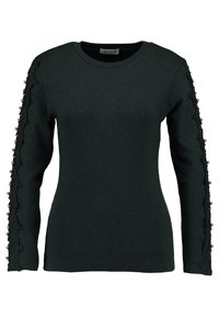 Chemise à manches longues vert foncé avec un col rond. Dotée de bordures en dentelle et d'ornements de couleur dorée le long des manches. Texture de tissu douce.