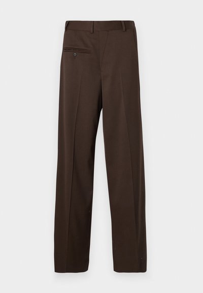 Calças castanhas sob medida com um corte ligeiramente solto, apresentando um único bolso traseiro com fecho de botão e uma textura de tecido suave.
