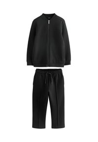 Sudadera negra con cremallera, cuello acanalado y dos bolsillos frontales, combinada con pantalones jogger negros de cintura elástica. Textura suave.