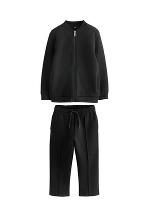 Sweat à zip noir avec col côtelé et deux poches avant, associé à un pantalon de jogging noir à taille élastiquée assorti. Texture lisse.