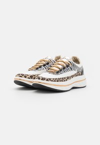 Sneakers con stampa leopardata e design a righe, con lacci in tono oro, materiali bianchi e neri, suole testurizzate e una robusta intersuola bianca.