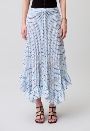 Falda midi plisada azul claro con lunares negros, paneles geométricos transparentes, dobladillo con volantes, combinada con sandalias negras de tiras con detalles en forma de corazón dorados.