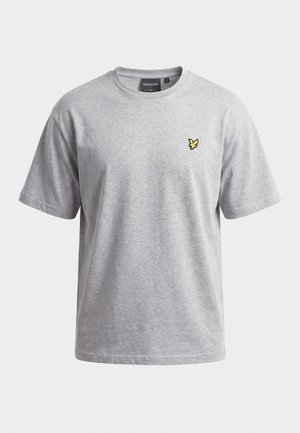 T-shirt gris clair à manches courtes avec col rond, portant un petit logo d'oiseau jaune sur le côté gauche de la poitrine et une étiquette de marque noire à l'intérieur de l'encolure.