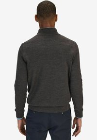 Tummanharmaa neulepaita, jossa on korkea kaulus, pitkät hihat ja ribattu helma. Sujuva pinta, jossa on hienovaraisia ompeluyksityiskohtia.