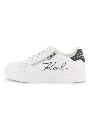 White leather sneakers with a thick white sole, featuring a side zip, black accents, and "Karl" in cursive on the side. Studded detail at the heel.