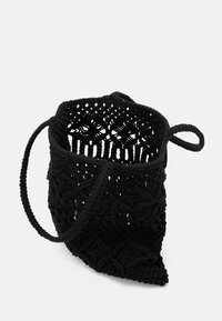 Háčkovaná černá taška s texturovaným designem, s výběžkovou základnou a dvěma uchy. Otevřený vršek odhaluje prostorný interiér.