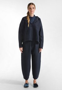 Mörkblått sweat set som består av en kort hoodie med en framficka och vida byxor. Mjuk textur, avslappnad passform och rundade fållar.