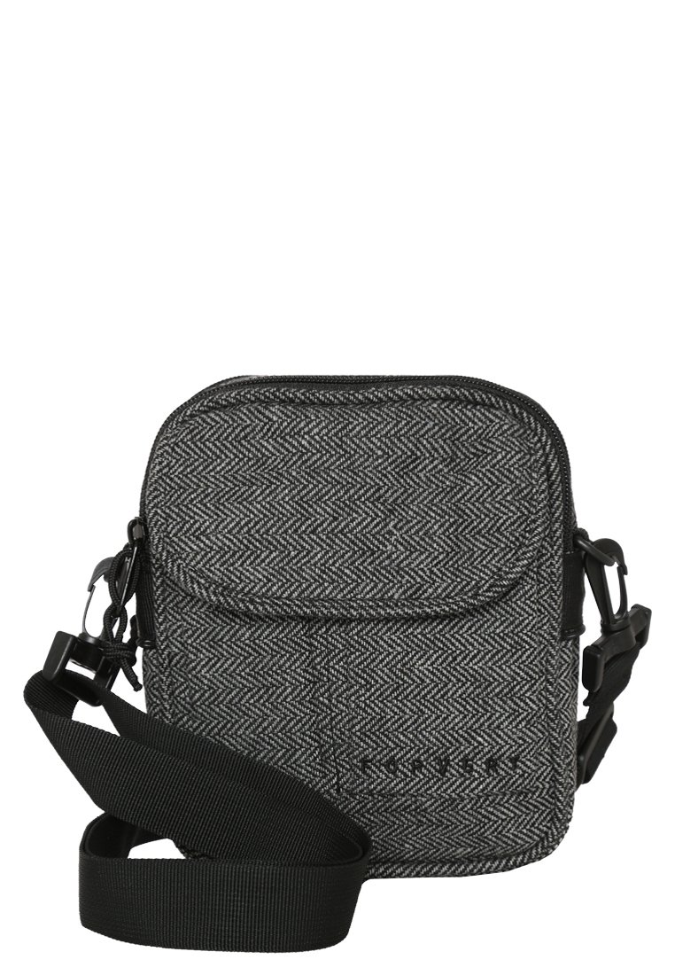 Bolso cruzado gris con patrón de espiga, correa ajustable negra, cierre superior con cremallera y bolsillo en la parte frontal para almacenamiento adicional.