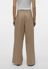 Beige højtaljede bukser med vide ben, plisseret design, skræddersyet pasform og glat tekstur. Ingen synlige lommer eller hardwaredetaljer.