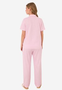 Růžový pruhovaný dvoudílný pyžamový set se short-sleeve košili a dlouhými kalhotami, vyrobený z měkké tkaniny. Jednoduchý límec a volný střih.