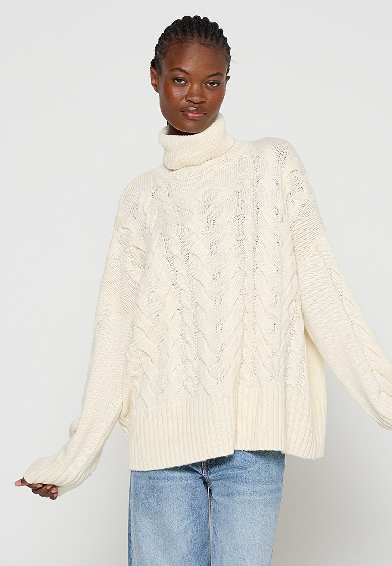 Grobe Strickpullover mit Rollkragen in Creme. Verfügt über gerippte Bündchen und Saum. Lockere Passform mit texturiertem Muster über das gesamte Kleidungsstück.