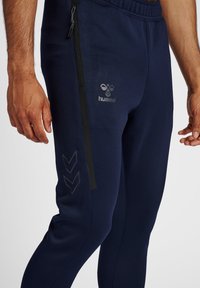 Marinemarine sportbroek met een slim fit, voorzien van een ritszak, logodetail en contrasterende zijstrepen met chevronpatronen.