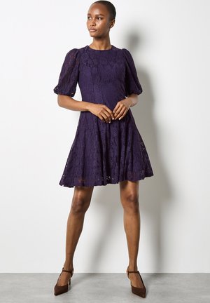 Robe en dentelle violette avec un col rond, des manches bouffantes et une silhouette en A. Présente un ourlet au-dessus du genou et de délicats motifs floraux.