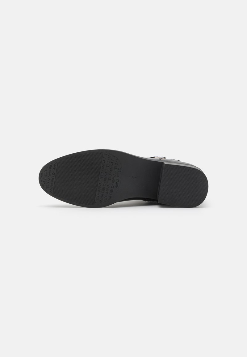 Suela de zapato de goma negra con patrones texturizados y letras en relieve. Bordes suaves y ligera textura de agarre para tracción.