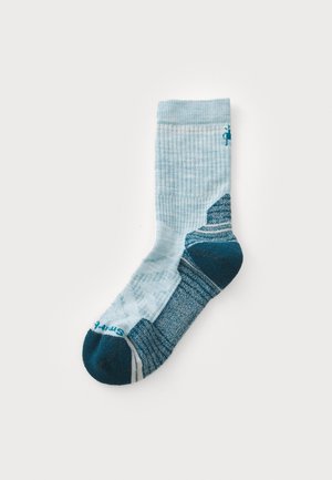 Valkoinen sukka, joka on valmistettu tekstuurista kankaasta, sisältää tummemman sinisen kantapään ja varpaankohdan, jossa on raidallinen kuvio ja "Smartwool"-logo varpaankohdassa.