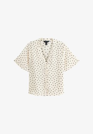 Blouse crème à manches courtes avec un décolleté en V, ornée d'un motif floral noir et de boutons sur le devant. Fabriquée en tissu léger.