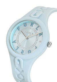 Reloj de silicona azul claro con una esfera redonda, acentos metálicos y letras adornadas con cristales que forman "FURLA". Correa texturizada con un diseño trenzado.