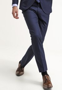 Dark blue tailored dress pants, featuring a slim fit, smooth fabric, and subtle crease detailing, paired with brown leather dress shoes.