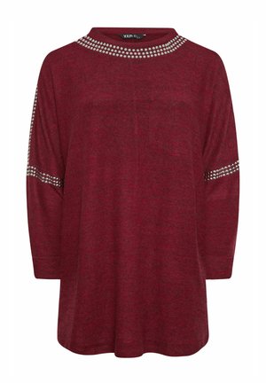 Bordowy top z szerokim dekoltem, ozdobiony srebrnymi ćwiekami wzdłuż kołnierza i rękawów. Wykonany z miękkiego, teksturowanego materiału. Luźny krój.
