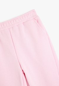 Lichtroze joggingbroek met een zachte textuur, elastische tailleband en zijzakken; heeft een ontspannen pasvorm en een gladde stofafwerking.