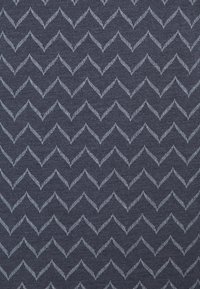 Námořnická látka s chevron vzorem ve světle modré barvě. Materiál vypadá texturovaně, s alternativními cik-cak liniemi vytvářejícími dynamický vizuální efekt.