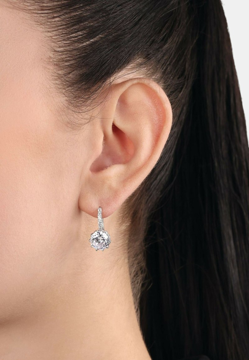 Orecchini a pendente in tono argento con una pietra preziosa rotonda e trasparente incastonata con griffe, e un accento brillante e texture sopra.