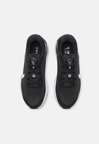 Scarpe da ginnastica nere con tomaia in mesh testurizzato, accenti bianchi e lacci rotondi. Caratterizzano un interno imbottito e una suola pronunciata per supporto.